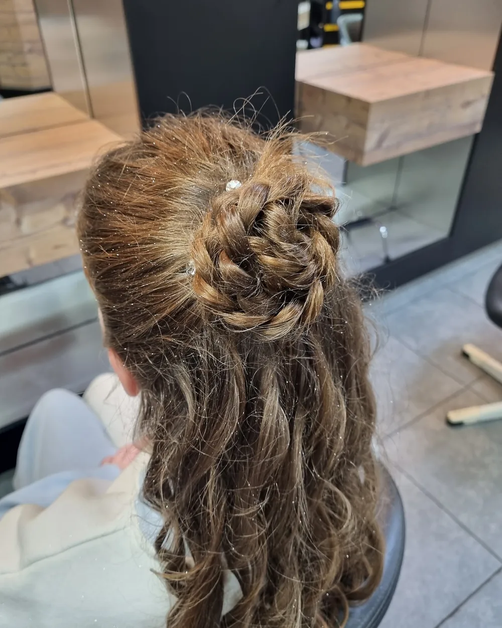 Half opgestoken krullen met een gevlochten knot en pareltjes
